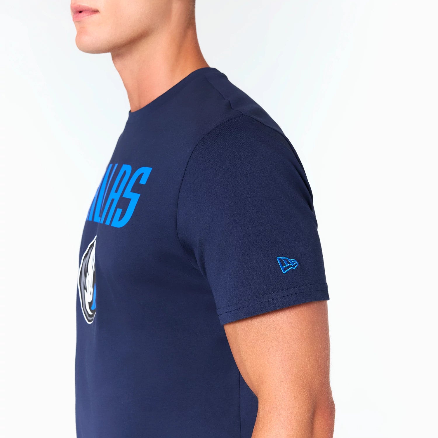 New Era Dallas Mavericks NBA Navy T-Shirt, side view showing a navy short-sleeved shirt with the team name in blue across the chest, a Mavericks logo below, and an embroidered New Era logo on the sleeve.