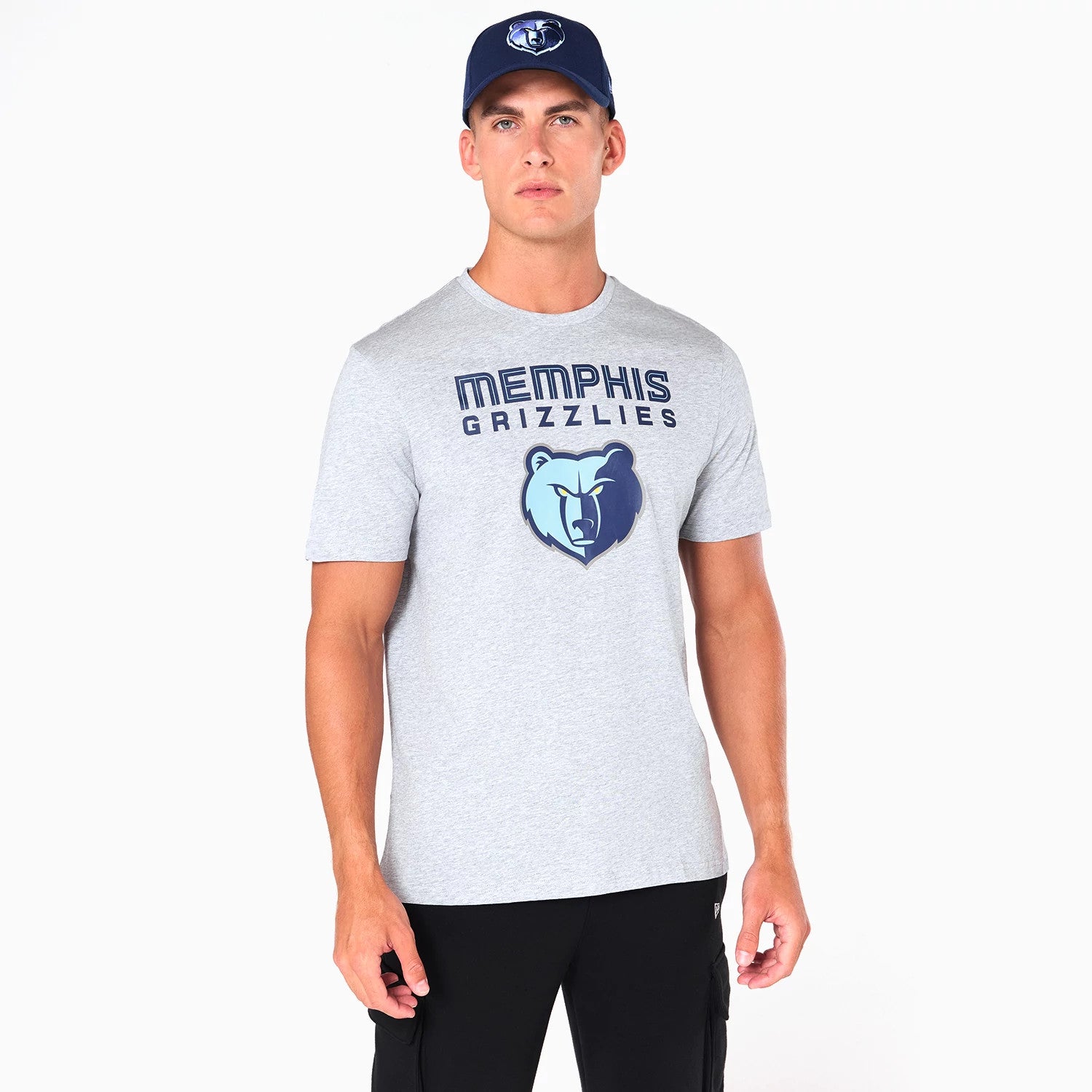 New Era Memphis Grizzlies NBA Grey T-Shirt, front view showing the grey fabric with the team name in navy blue above a large Grizzlies bear logo, worn by a model paired with a matching cap featuring an embossed logo.