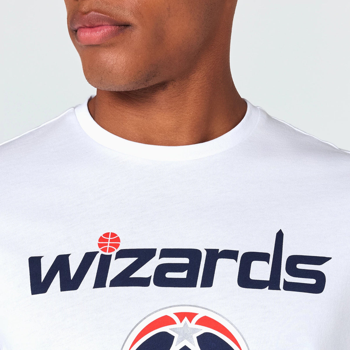 New Era Washington Wizards NBA White T-Shirt, front view showing the large wizards text in dark blue with a red basketball dotting the i, positioned across the centre of the chest with a portion of the team logo underneath.
