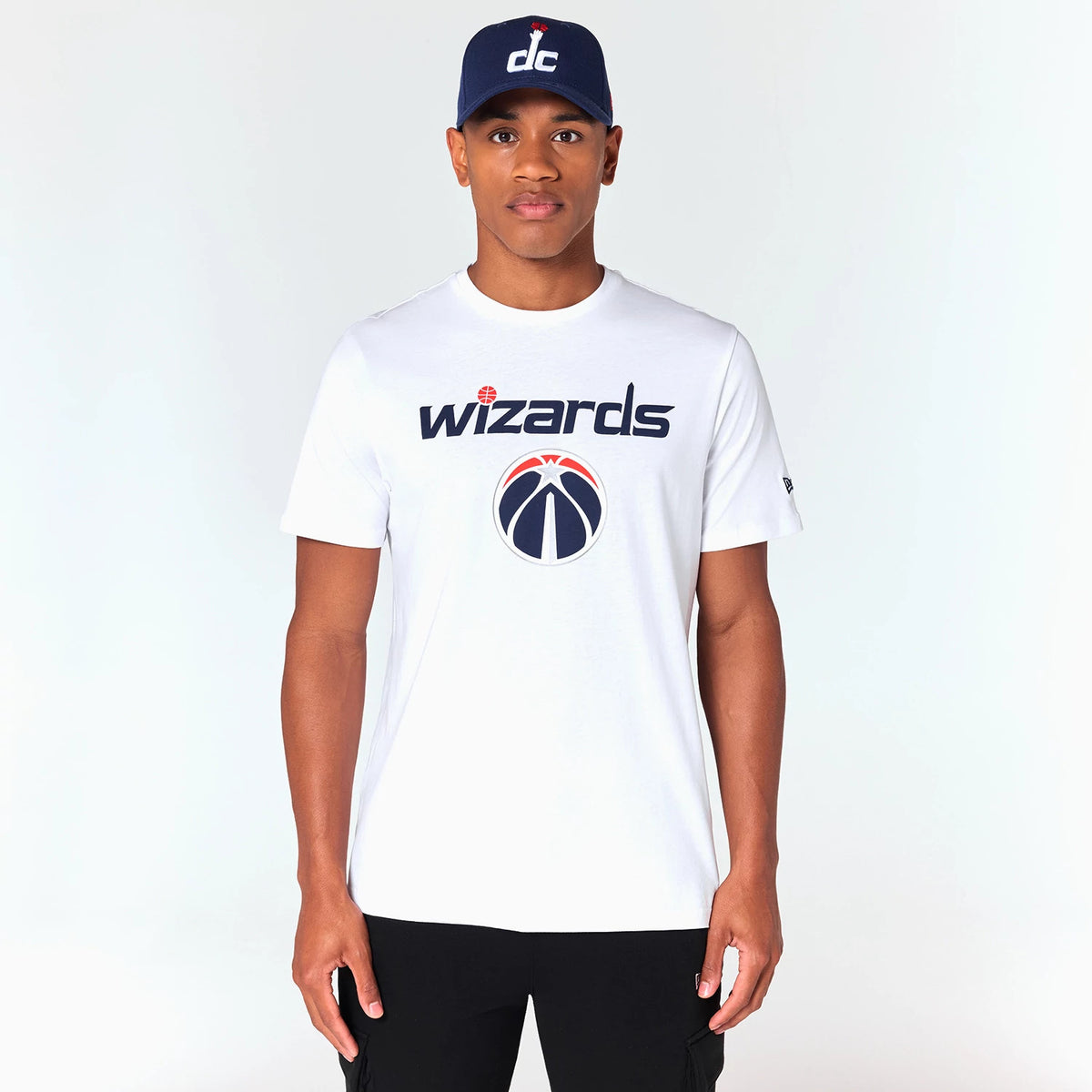 New Era Washington Wizards NBA White T-Shirt, front view showing the Wizards logo and text printed prominently on the chest, with a raised New Era logo on the left sleeve and a navy cap featuring a raised white dc logo worn by the model.
