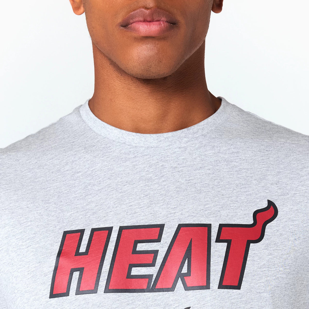 New Era Miami Heat NBA Grey T-Shirt, front view showing a soft grey fabric with the bold red HEAT lettering and flame detail across the chest, visible on a model from the neck to mid-torso.