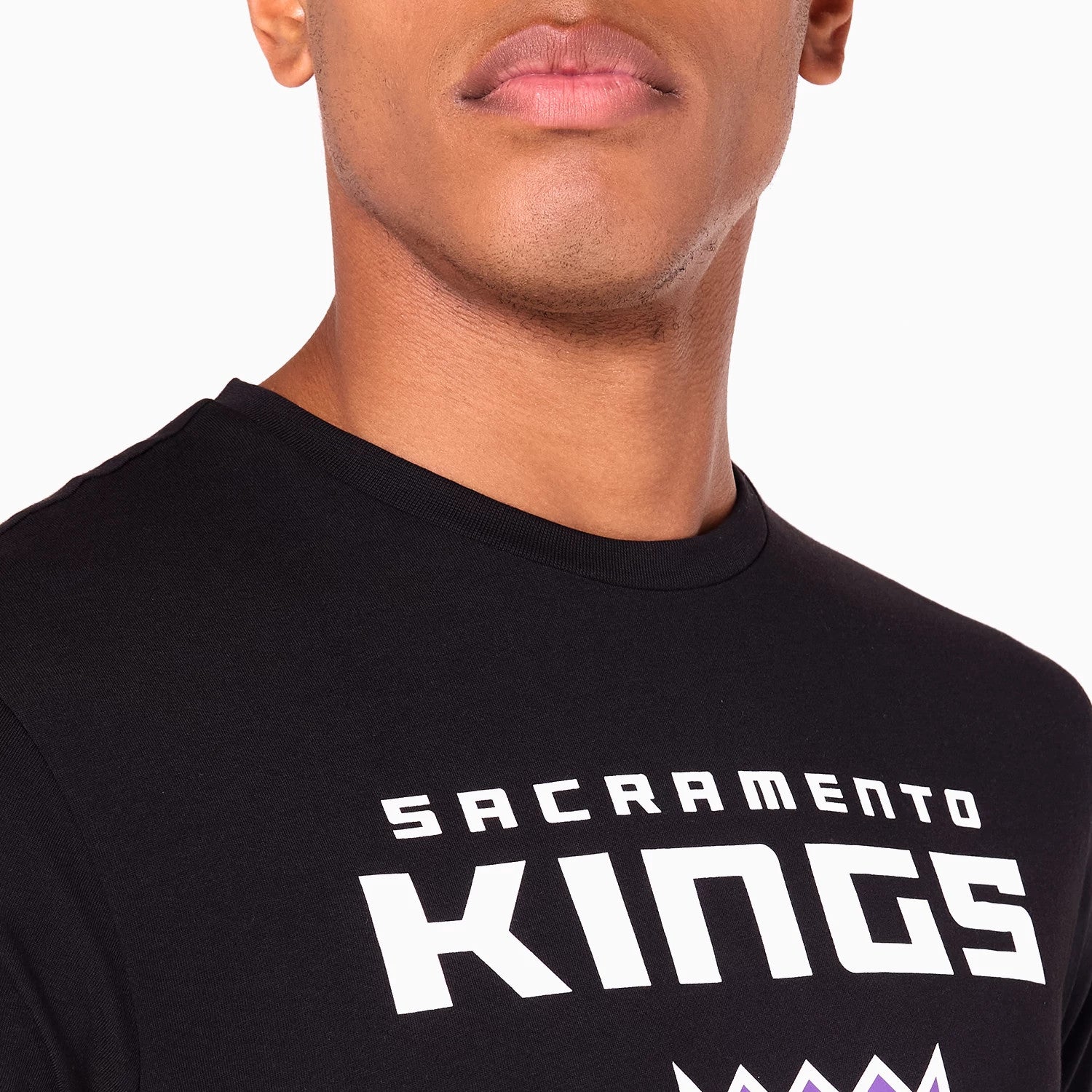 New Era Sacramento Kings NBA Black T-Shirt, front view showing the bold white Sacramento Kings text printed across the chest, visible portion of a purple crown graphic below, and a round neckline.