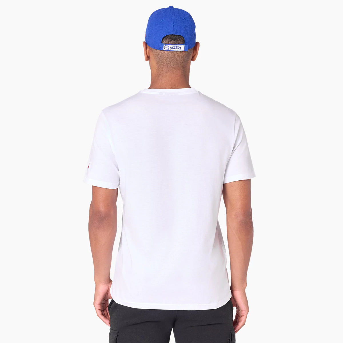 New Era Philadelphia 76ers NBA White T-Shirt, on-model view showing a plain back of the white shirt with short sleeves, paired with a blue cap that has a raised rectangular logo at the back.