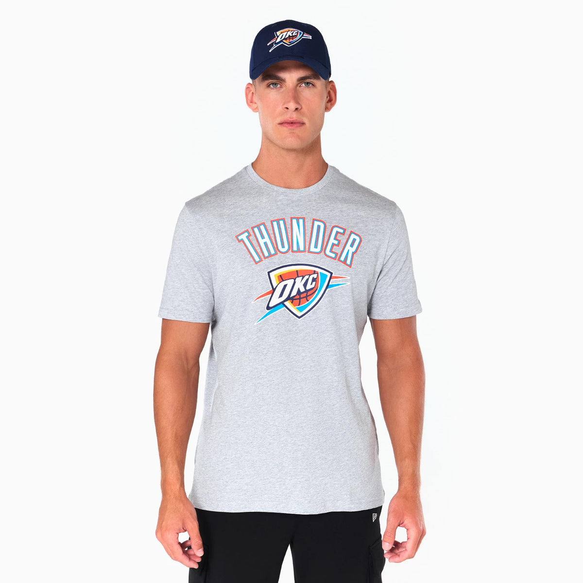 New Era Oklahoma City Thunder NBA Grey T-Shirt, front view showing Thunder text in blue and orange above the OKC logo on a grey background, a man wearing a navy cap with an embossed OKC logo.