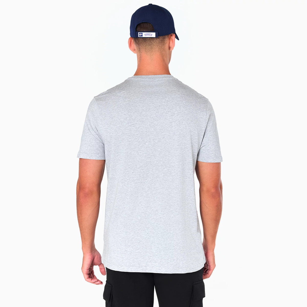 New Era Oklahoma City Thunder NBA Grey T-Shirt, rear view showing a plain light grey short-sleeve shirt worn by a man facing away, with a navy cap displaying a raised logo on the back above the cap's closure.