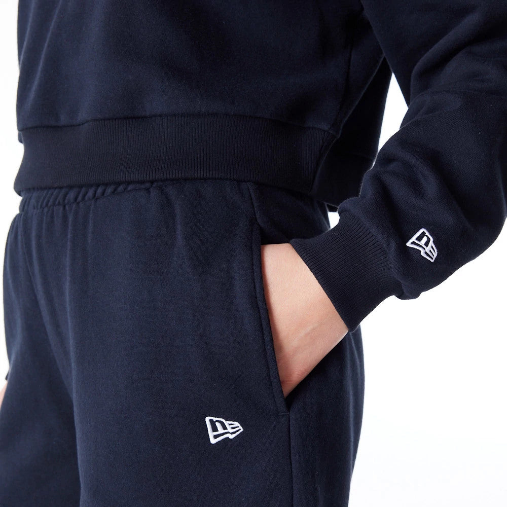 New Era New York Yankees Womens MLB League Essential Black Crop Crew Neck Sweatshirt, close-up showing the white New Era flag logo embroidered on the left forearm and the side of the matching trousers, with ribbed cuffs and side pocket detail.