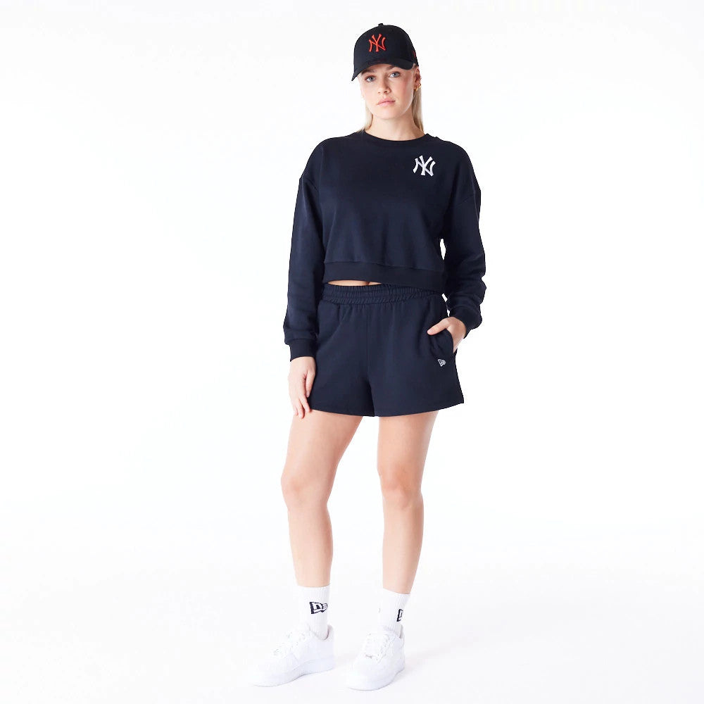 New Era New York Yankees Womens MLB League Essential Black Crop Crew Neck Sweatshirt, on-model view with matching black shorts and cap, featuring the white Yankees logo on the left chest and a relaxed fit design.