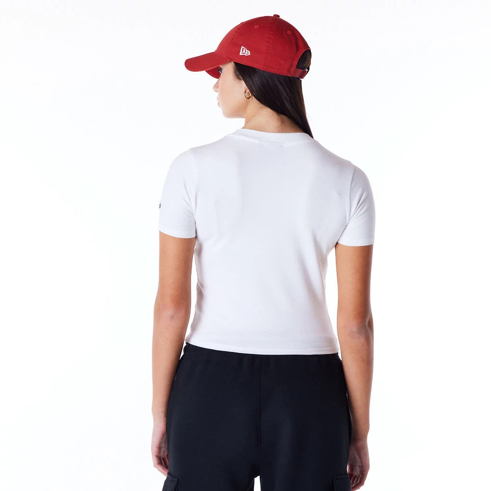 New Era Womens White Slim T-Shirt, on-model view showing the back of a white fitted t-shirt with short sleeves, paired with black trousers, and a red cap featuring an embossed New Era logo on the side.