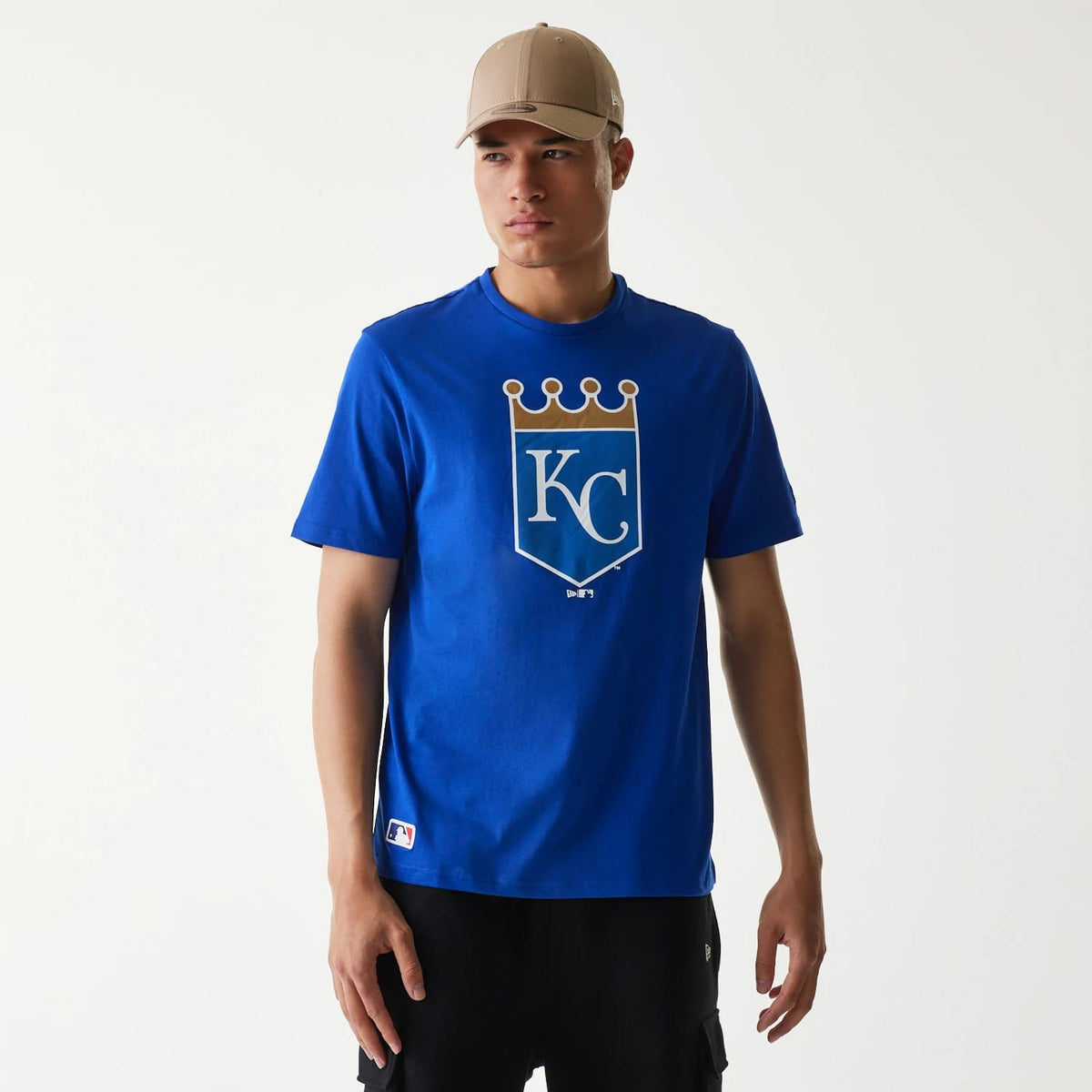 New Era Kansas City Royals MLB Regular Blue T-Shirt, on-model view showing a large printed shield logo with a crown on the chest, a New Era tag on the side and a small MLB logo near the hem in the corner.