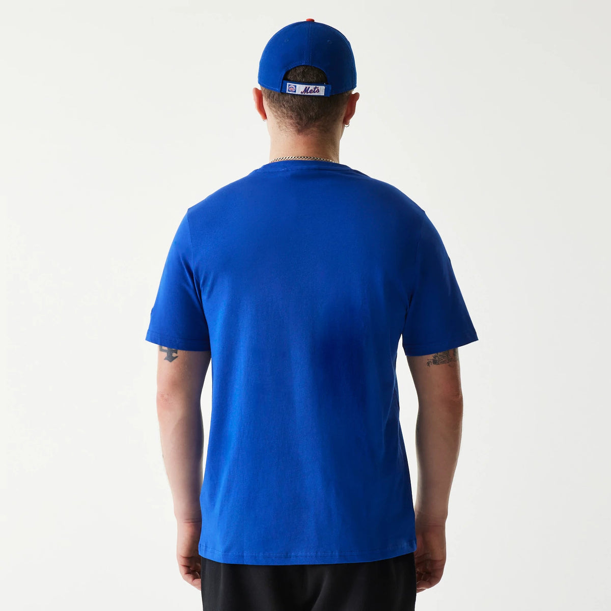 New Era New York Mets MLB Regular Blue T-Shirt, rear view showing the solid blue fabric with a straight hem, sleeves falling above the elbows, model wearing a matching blue cap with a debossed Mets logo centred on the back.