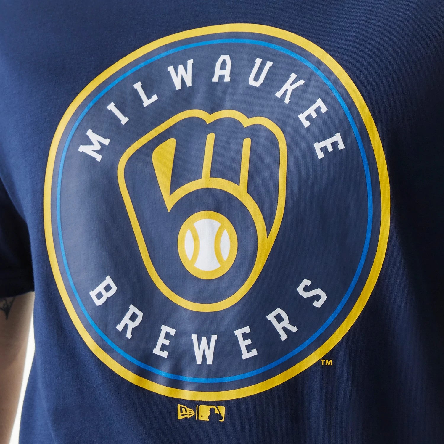 New Era Milwaukee Brewers MLB Regular Dark Blue T-Shirt, front view showing the large printed Brewers logo in yellow and white on the chest, with a raised New Era logo in yellow at the lower edge.