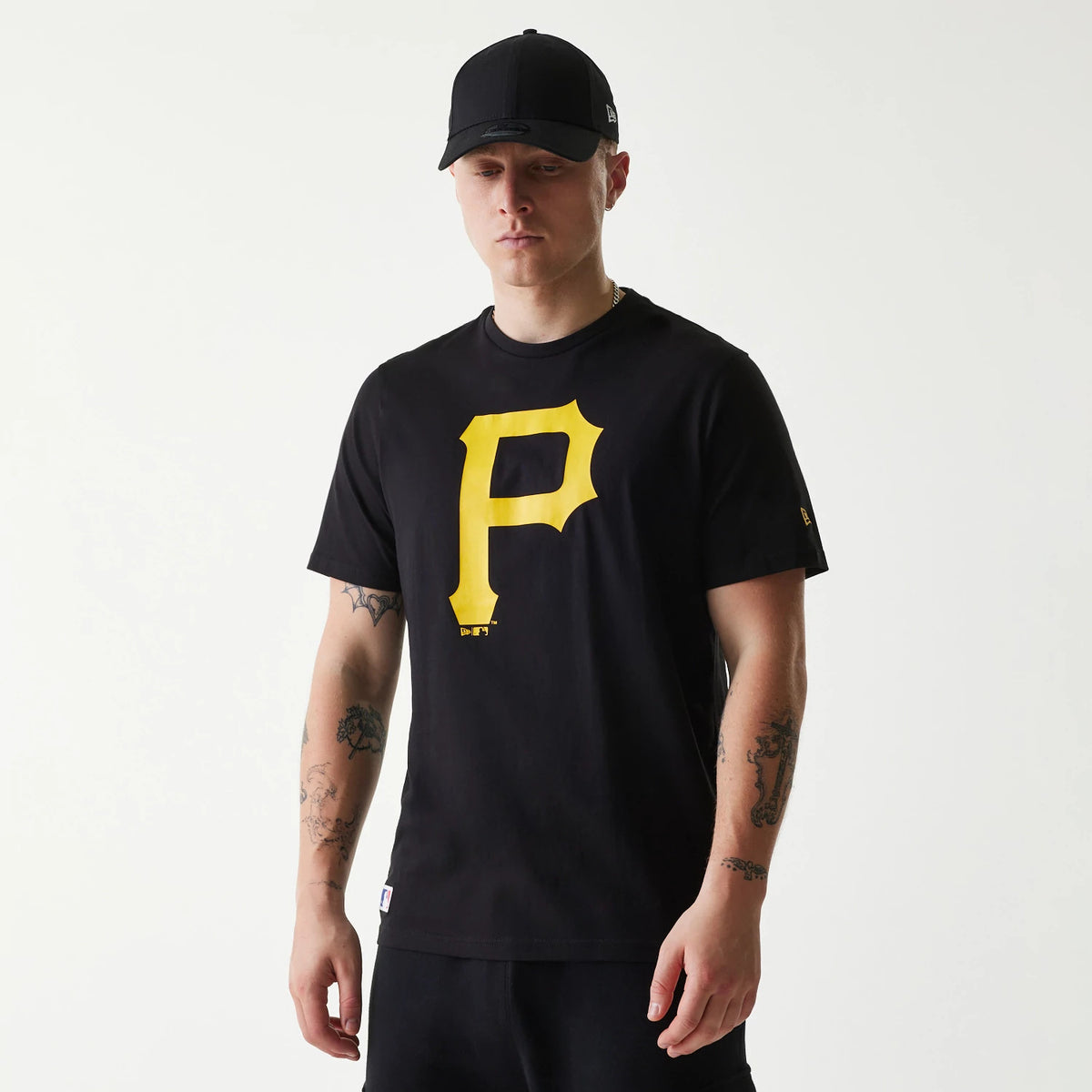 New Era Pittsburgh Pirates MLB Regular Black T-Shirt, on-model view showing a man wearing the black T-shirt with a large yellow P logo on the chest, paired with a black cap featuring a raised New Era logo on the side.