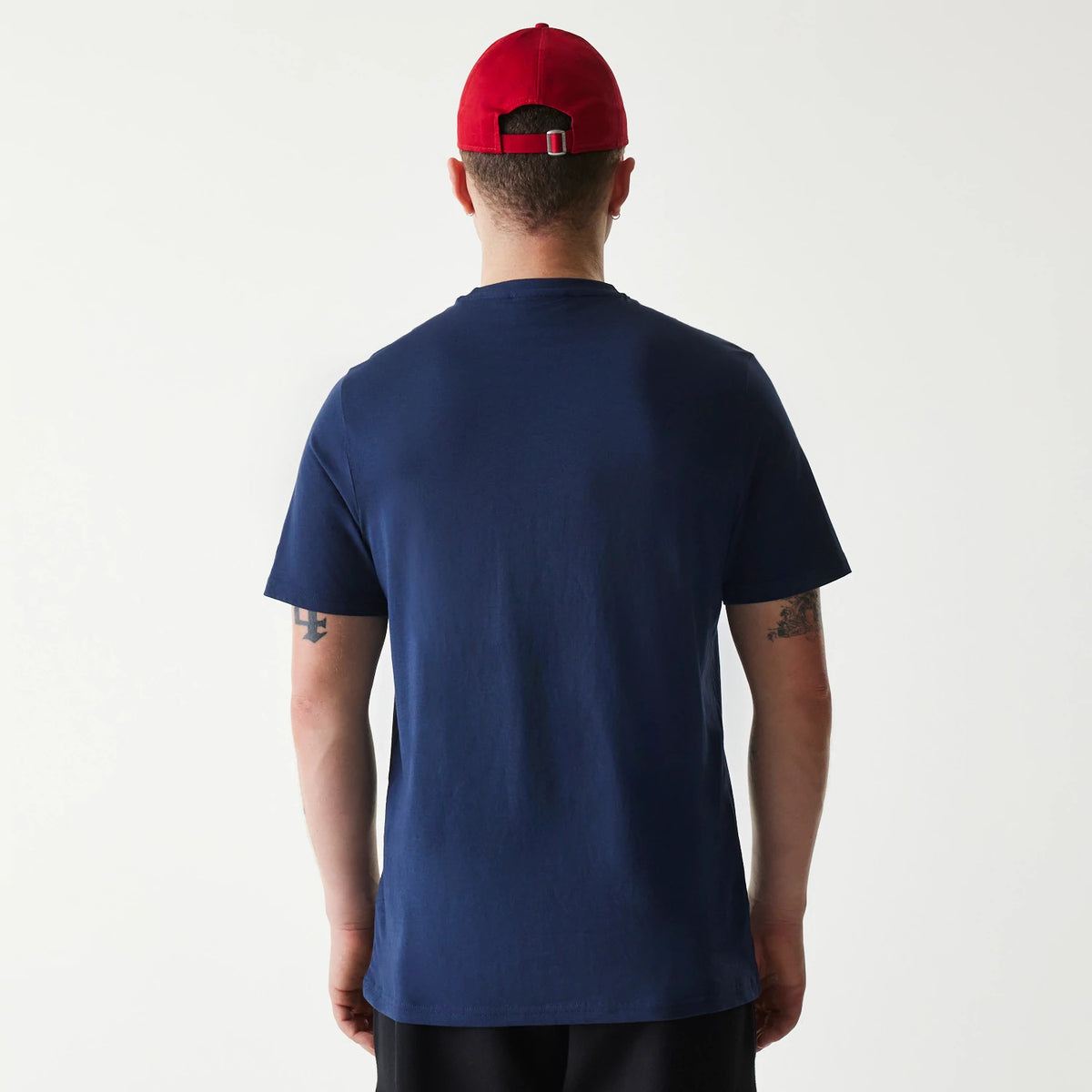 New Era Texas Rangers MLB Regular Dark Blue T-Shirt, rear view showing the simple dark blue fabric without any visible design or logo, worn by a model facing away, paired with a red cap that features an adjustable back strap.