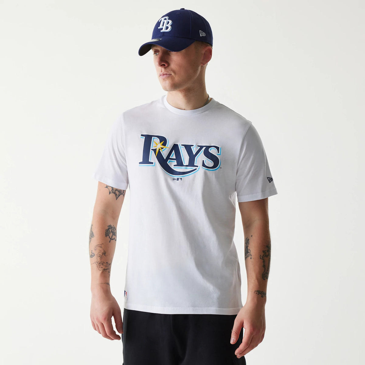 New Era Tampa Bay Rays MLB Regular White T-Shirt, on-model view showing the bold navy team logo centred on the chest, with the model wearing a navy cap featuring a raised New Era logo on the side.