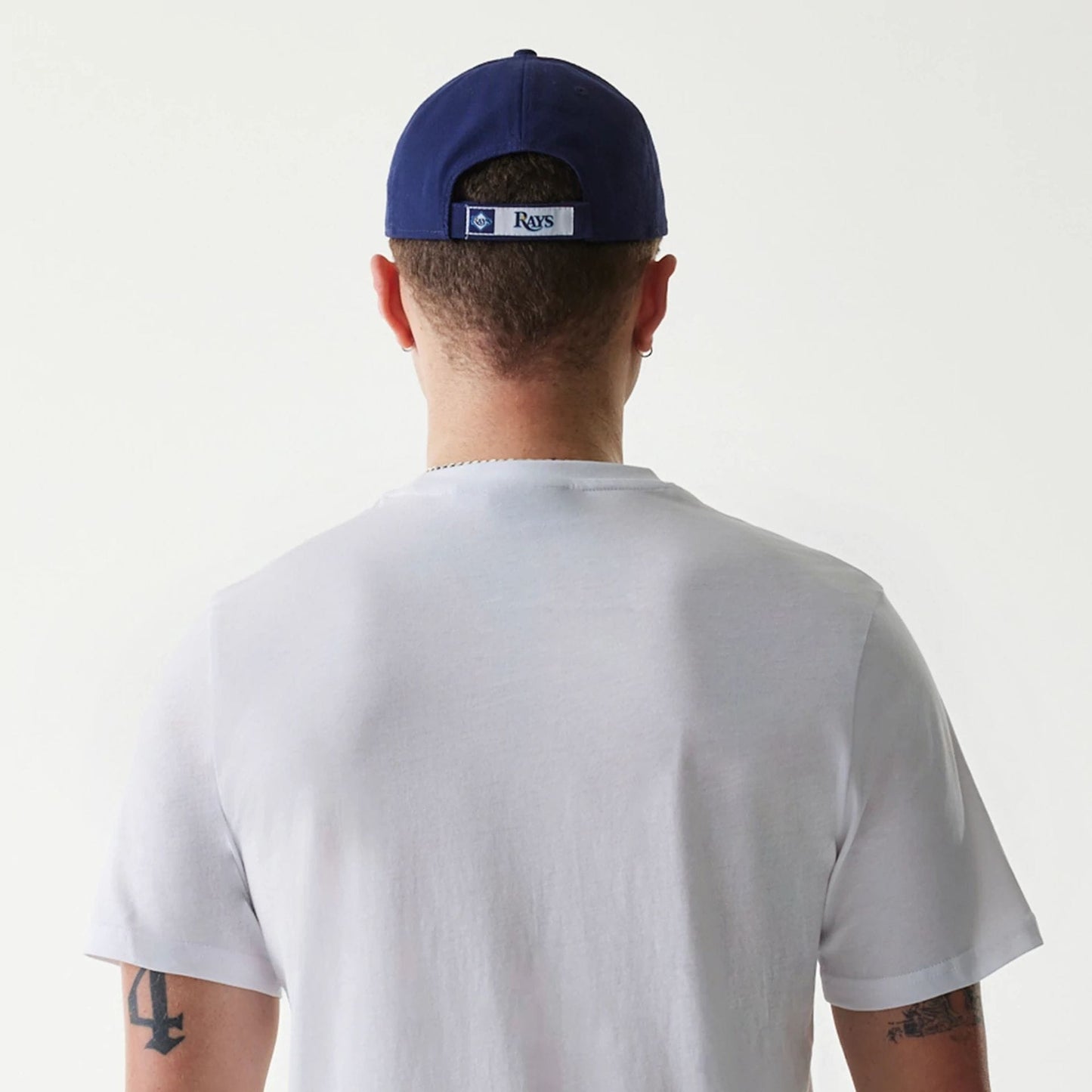 New Era Tampa Bay Rays MLB Regular White T-Shirt, on-model rear view showing the plain white back of the t-shirt, a blue cap worn with an embroidered Rays logo patch centred above the opening on the cap.