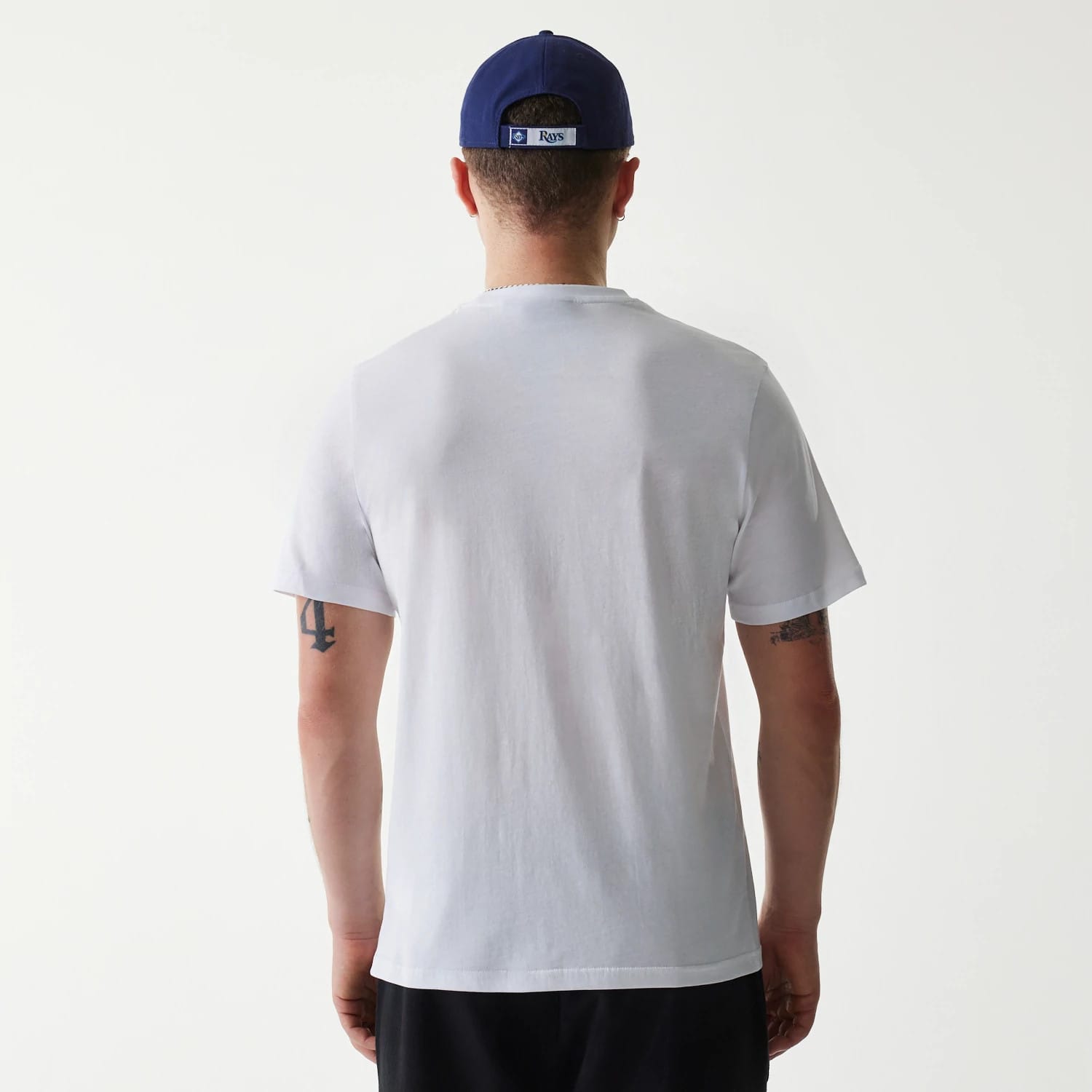 New Era Tampa Bay Rays MLB Regular White T-Shirt, on-model rear view showing the plain white back design, straight hem, and relaxed short sleeves, paired with a blue cap featuring a raised Rays logo at the back.