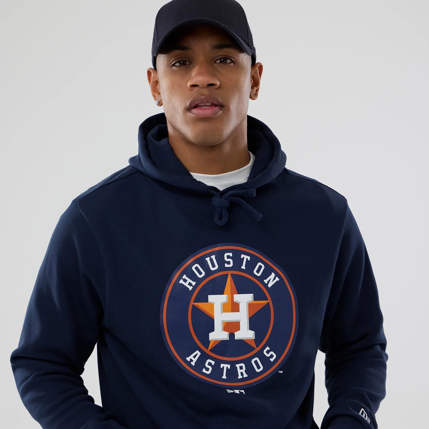 New Era Houston Astros MLB Dark Blue Pullover Hoodie, on-model view showing the dark blue hoodie with a prominent Houston Astros logo on the chest, drawstrings at the hood and a small embroidered New Era logo on the sleeve.