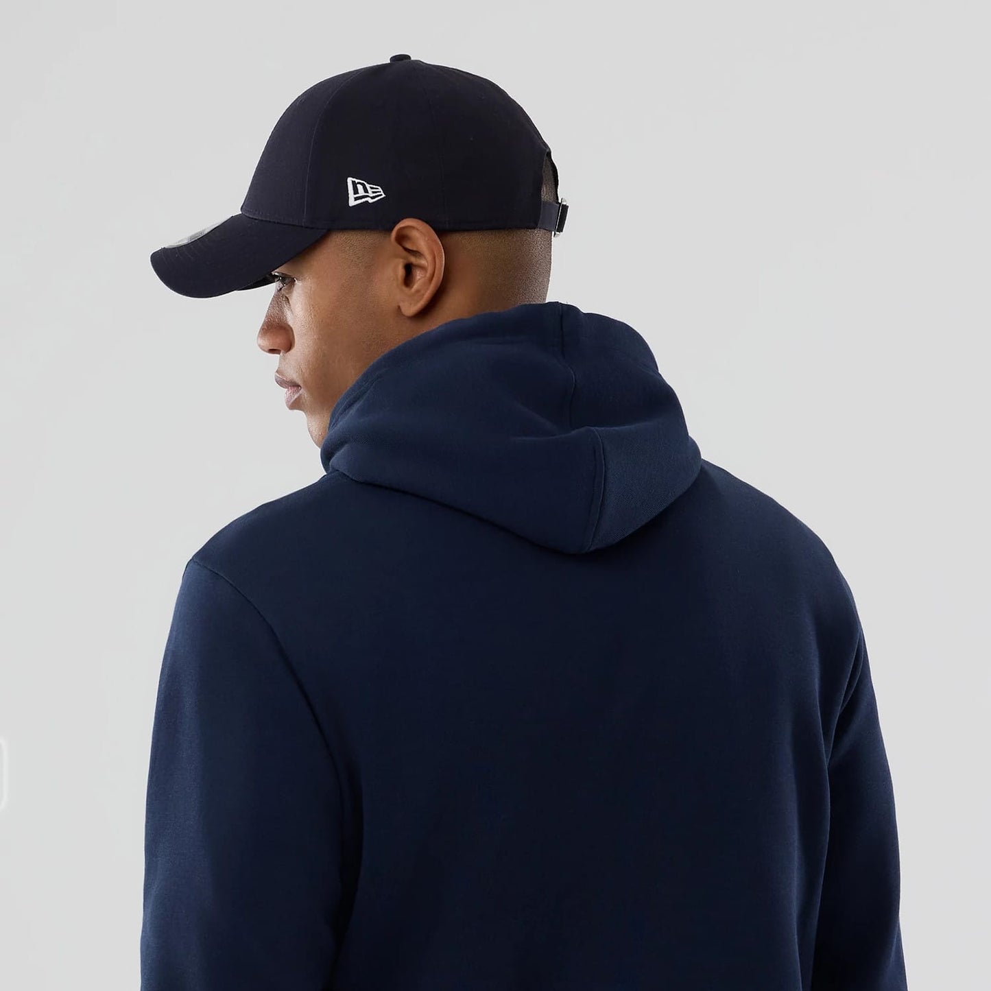 New Era Houston Astros MLB Dark Blue Pullover Hoodie, on-model view from the back showing the dark blue hood resting flat, paired with a dark cap featuring a raised New Era logo on the left side.