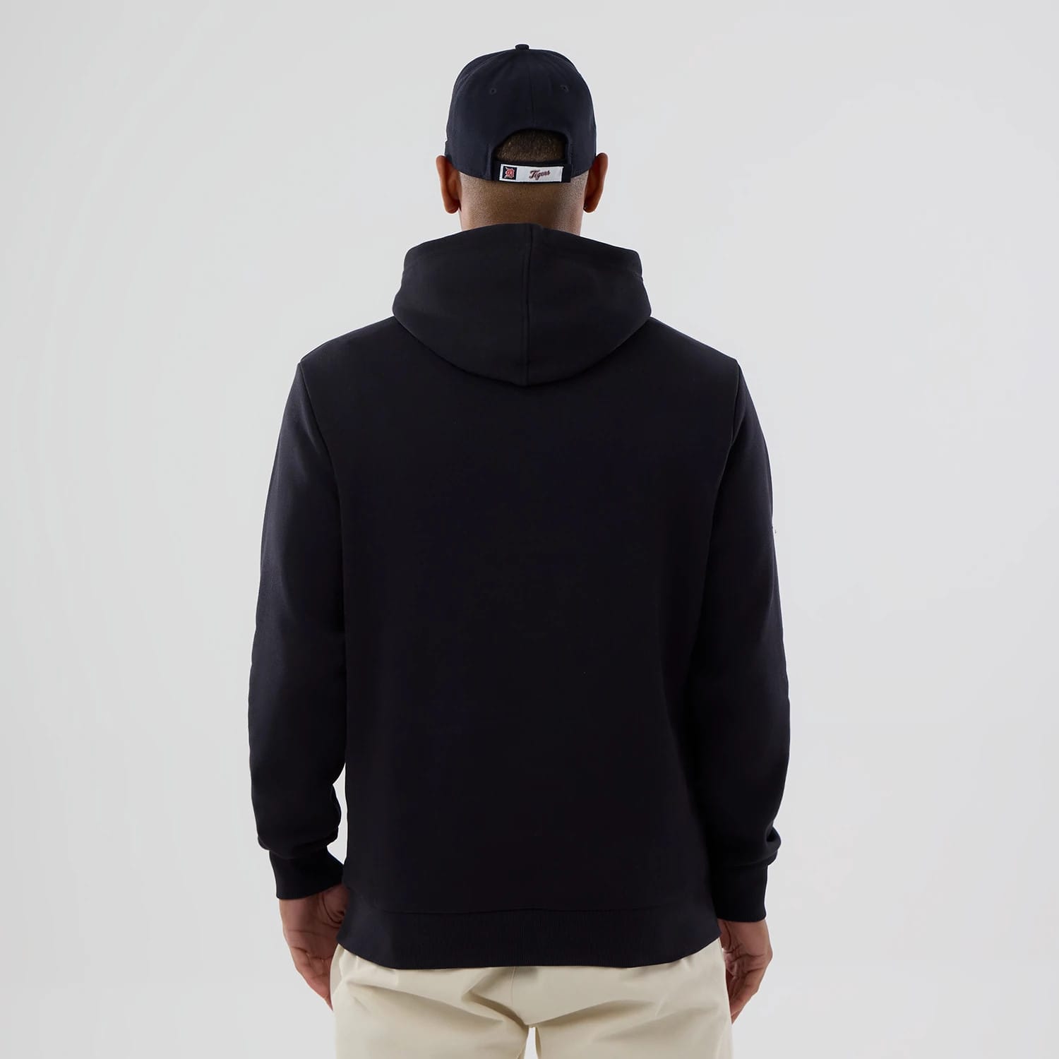 New Era Detroit Tigers MLB Navy Pullover Hoodie, rear view of the plain navy hoodie worn by a model, the hood resting on the back and a navy cap with a white embroidered logo on the cap's back.