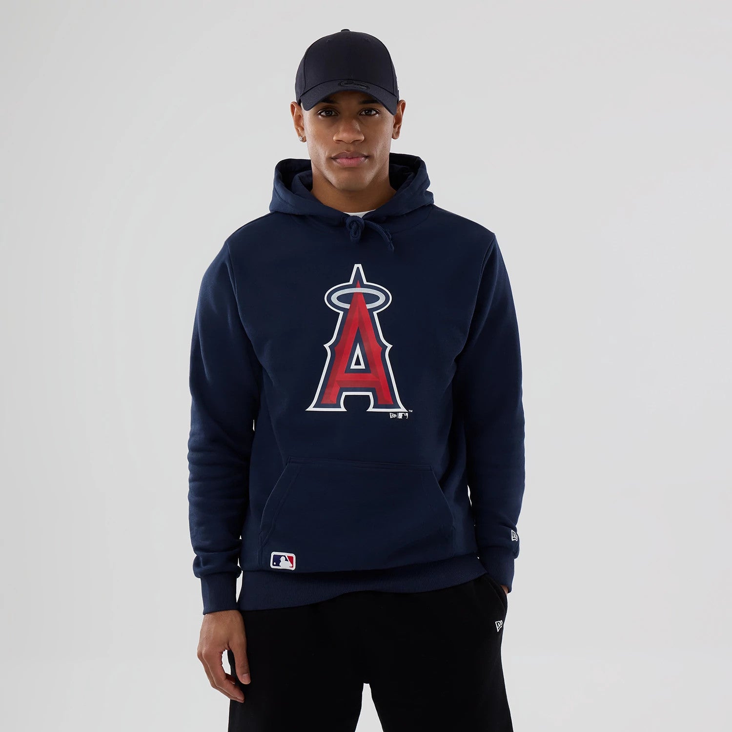 New Era LA Angels MLB Dark Blue Pullover Hoodie, on-model view showing the large red and white embroidered LA Angels logo centred on the chest, drawstring at the hood, and a debossed New Era logo on the left sleeve.
