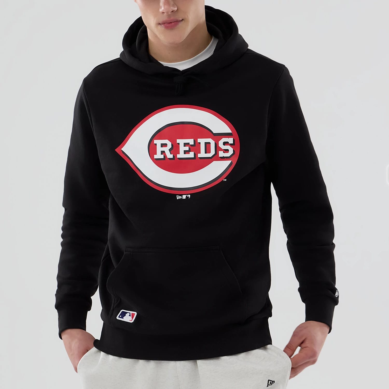 New Era Cincinnati Reds MLB Black Pullover Hoodie, front view showing the large red and white Reds logo printed on the chest, ribbed cuffs on the sleeves, a spacious kangaroo pocket below, and a raised New Era logo on the left wrist.