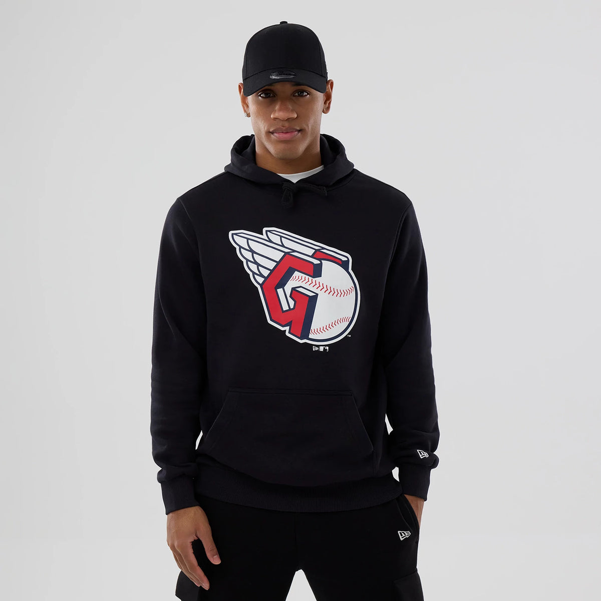 New Era Cleveland Guardians MLB Navy Pullover Hoodie, on-model view showing a large Cleveland Guardians logo on the front, with a hood and long sleeves, worn with a black cap featuring a raised New Era logo on the front.
