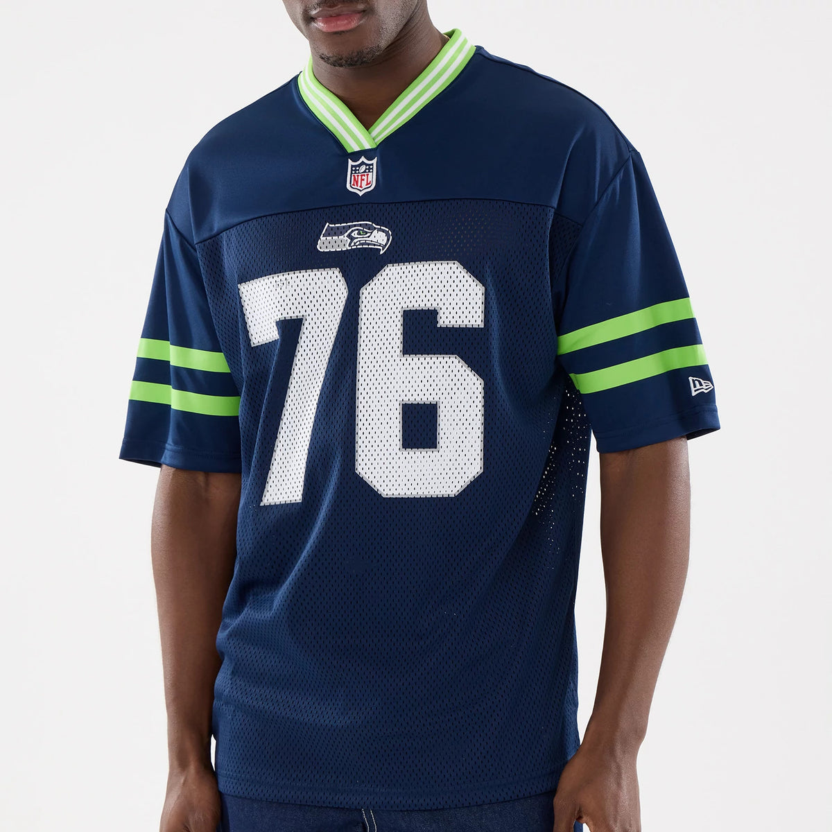 New Era Seattle Seahawks NFL Mesh Dark Blue Mesh Jersey, front view on a model showing the white number 76 on the chest, with a Seahawks logo above and green stripe accents on the sleeves beneath the New Era flag logo.