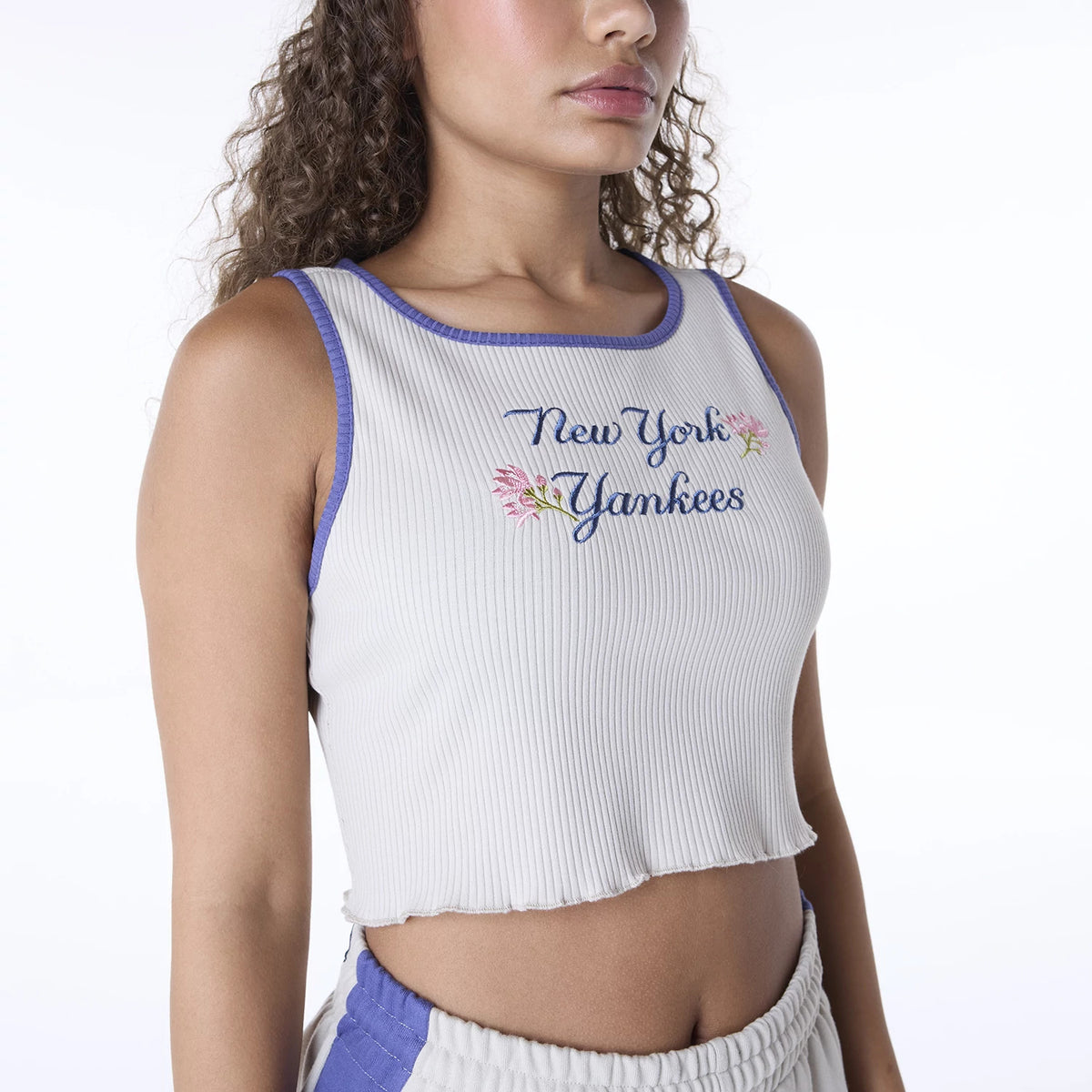 New Era New York Yankees Womens MLB Floral Cream Vest, on-model view with purple edging around the armholes and neckline, displaying blue New York Yankees embroidery with pink floral details on a ribbed fabric.