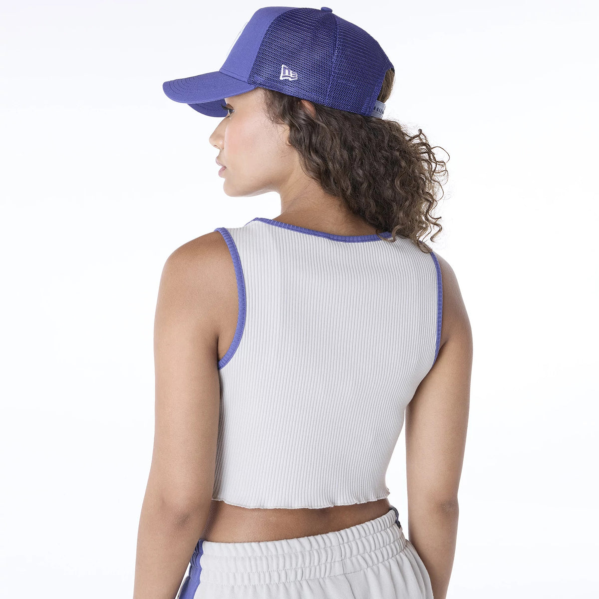 New Era New York Yankees Womens MLB Floral Cream Vest, back view on a model with contrasting blue neckline and arm trims, paired with a blue mesh-back cap featuring the New Era flag logo on the left side.