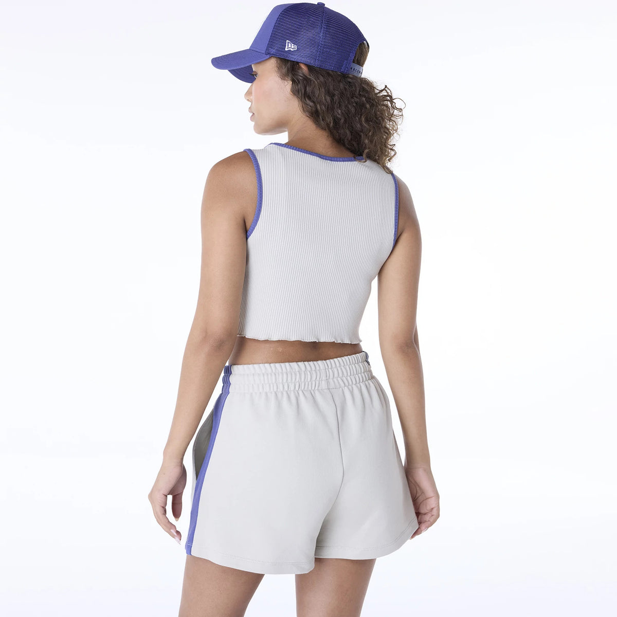 New Era New York Yankees Womens MLB Floral Cream Vest, back view on a model wearing a white vest with blue trim, paired with cream shorts featuring blue stripes, and a blue cap showing the New Era flag logo on the left side.