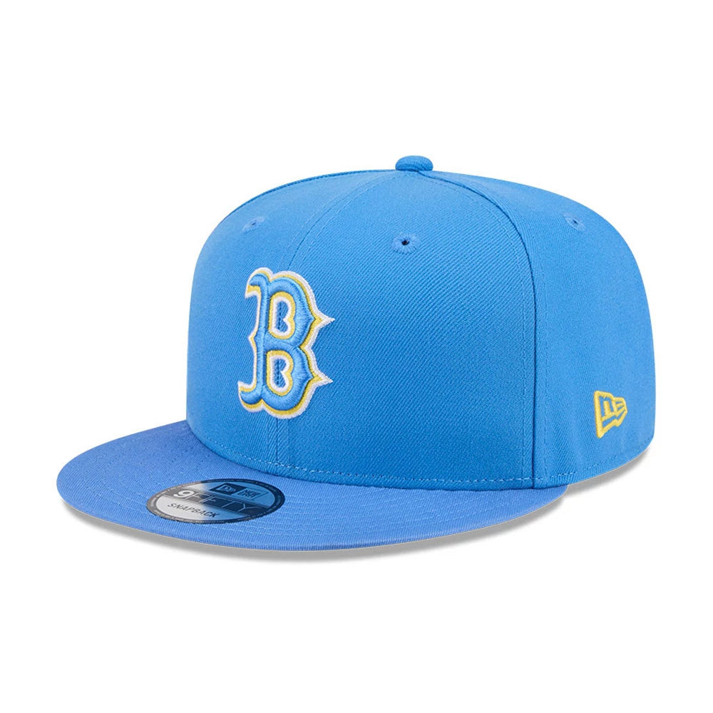 Boston Red Sox MLB Evergreen Blue New Era 9FIFTY Snapback Adjustable Cap, three-quarter view showing the raised yellow outlined B logo on the front panel, a blue flat visor with a 9FIFTY size sticker, and New Era flag logo on the left side.