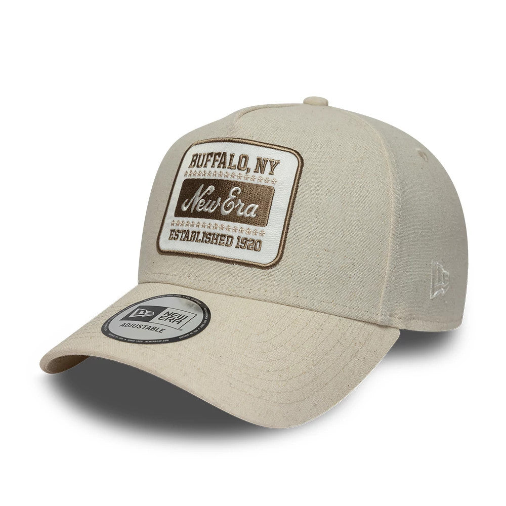 New Era Patch Line Cream New Era 9FORTY E-Frame Adjustable Cap, three-quarter view showing the brown embroidered patch on the front panel, cream curved visor with a 9FORTY size sticker, and New Era flag logo on the left side.