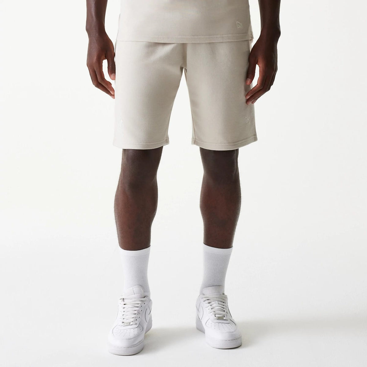 New Era New York Yankees MLB Raglan Cream Shorts, front view showing the cream fabric shorts with a raised New Era logo near the hem on the left leg, paired with white socks and trainers.