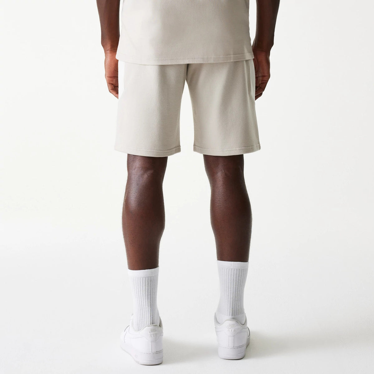 New Era New York Yankees MLB Raglan Cream Shorts, rear view showing the plain cream fabric of the shorts with an elastic waistband, worn by a model, extending slightly below the knee with a straight hem.
