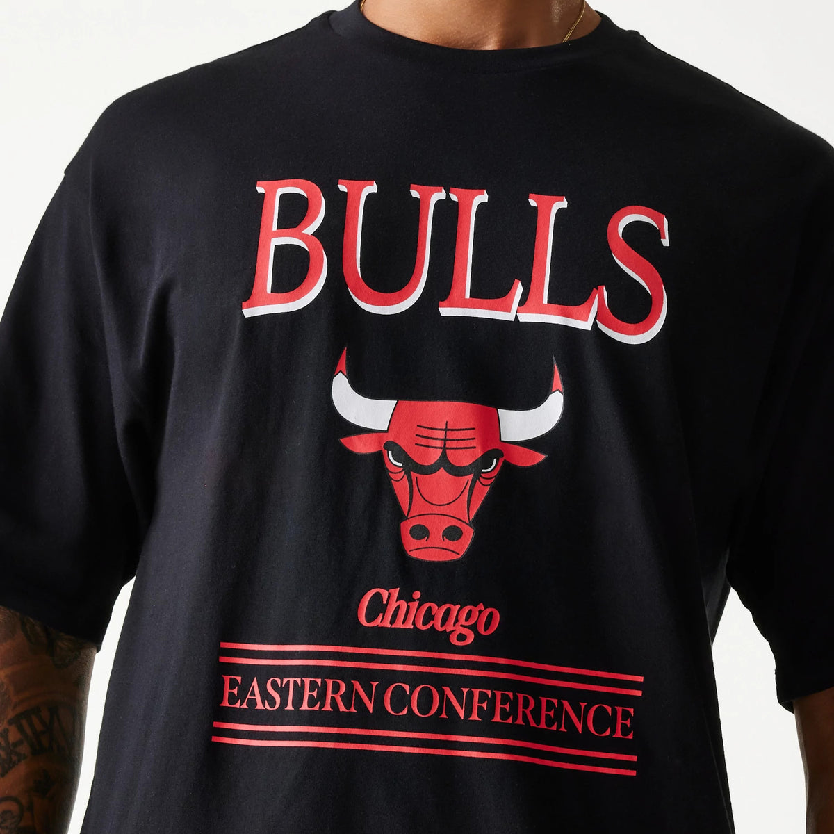 New Era Chicago Bulls NBA Team Graphic Black Oversized T-Shirt, front view showing the bold red Bulls logo with a bull graphic, Chicago text underneath, and Eastern Conference in red stripes on the black fabric.