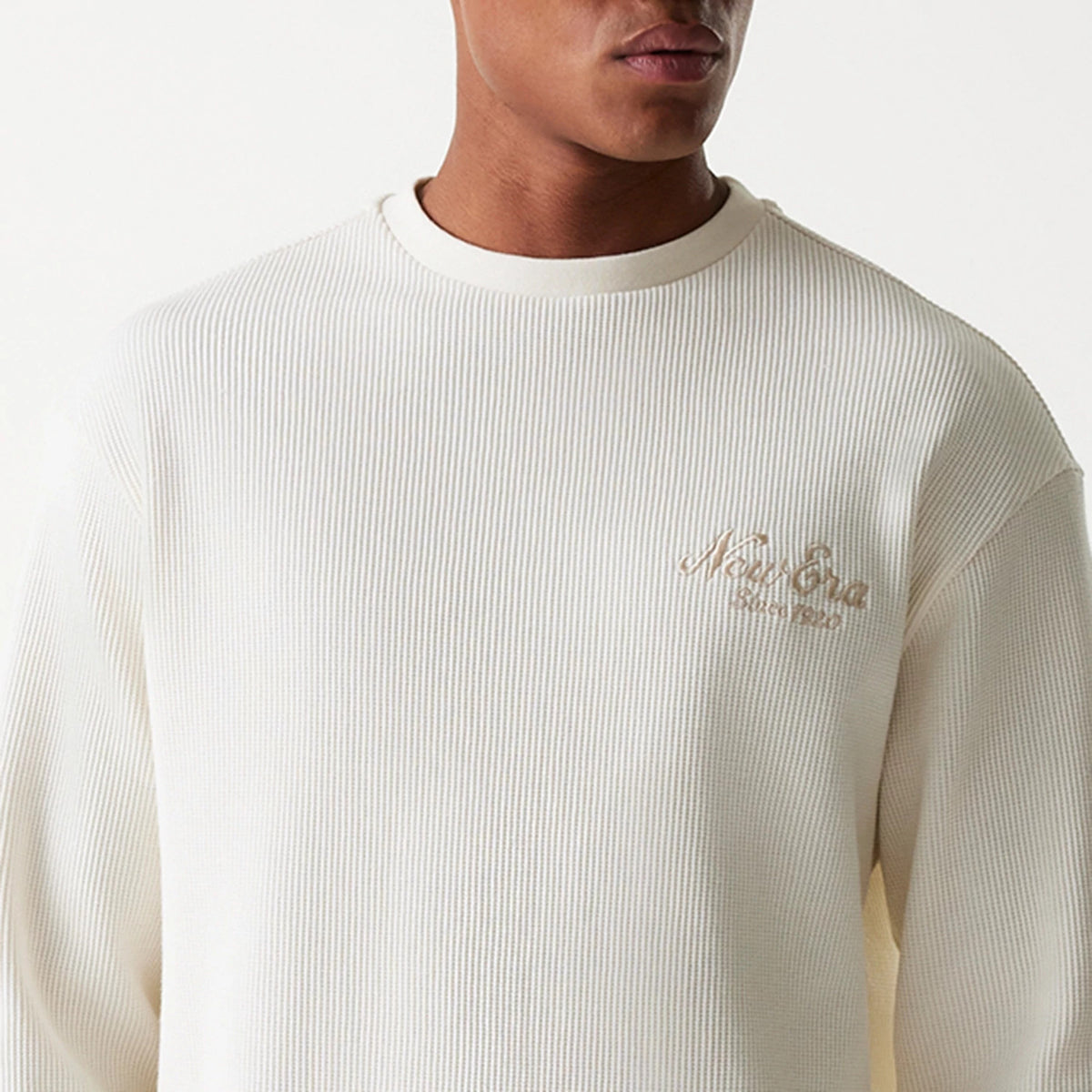New Era Waffle Open White Oversized Crew Neck Sweater, front view on a model with ribbed waffle texture and subtle New Era Script logo embroidered in beige on the chest, highlighting the relaxed fit.