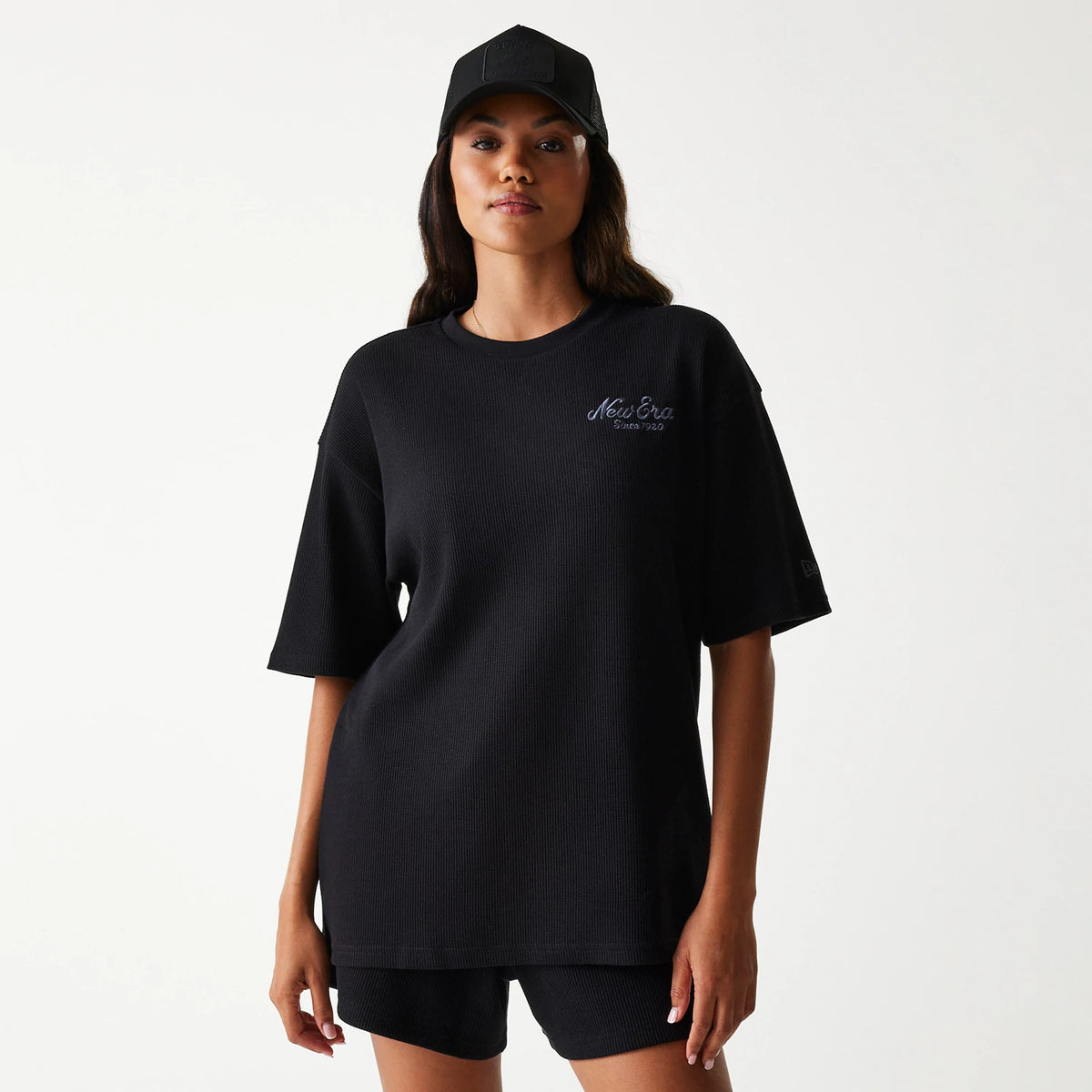 New Era Waffle Black Oversized T-Shirt, front view showing the relaxed fit black t-shirt with a raised New Era logo on the left chest, paired with a black cap featuring a raised logo on the front panel.