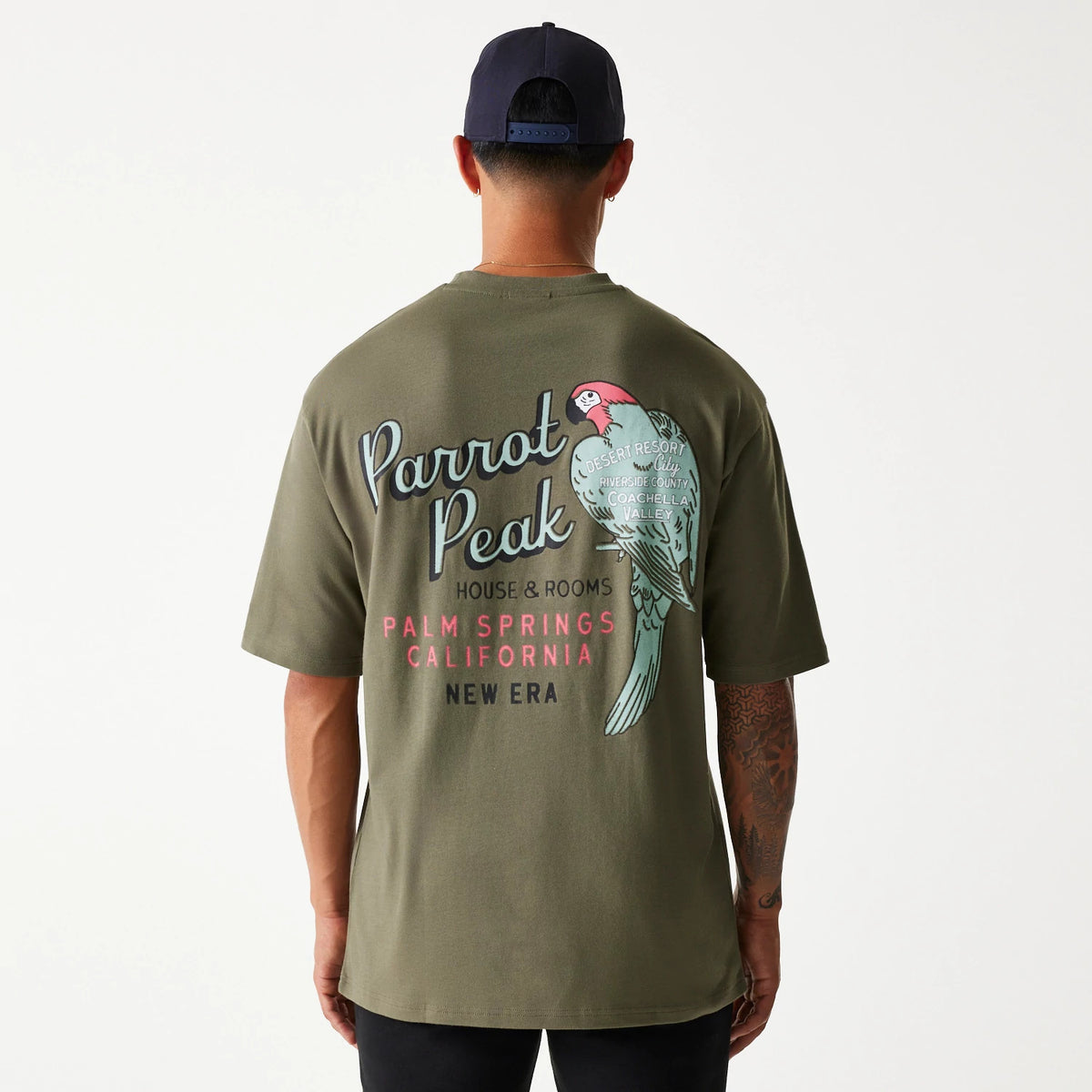 New Era Animal Graphic Green Oversized T-Shirt, rear view showing an illustrated parrot with text including 'Parrot Peak' and 'Palm Springs, California', printed on the back of the oversized green t-shirt.