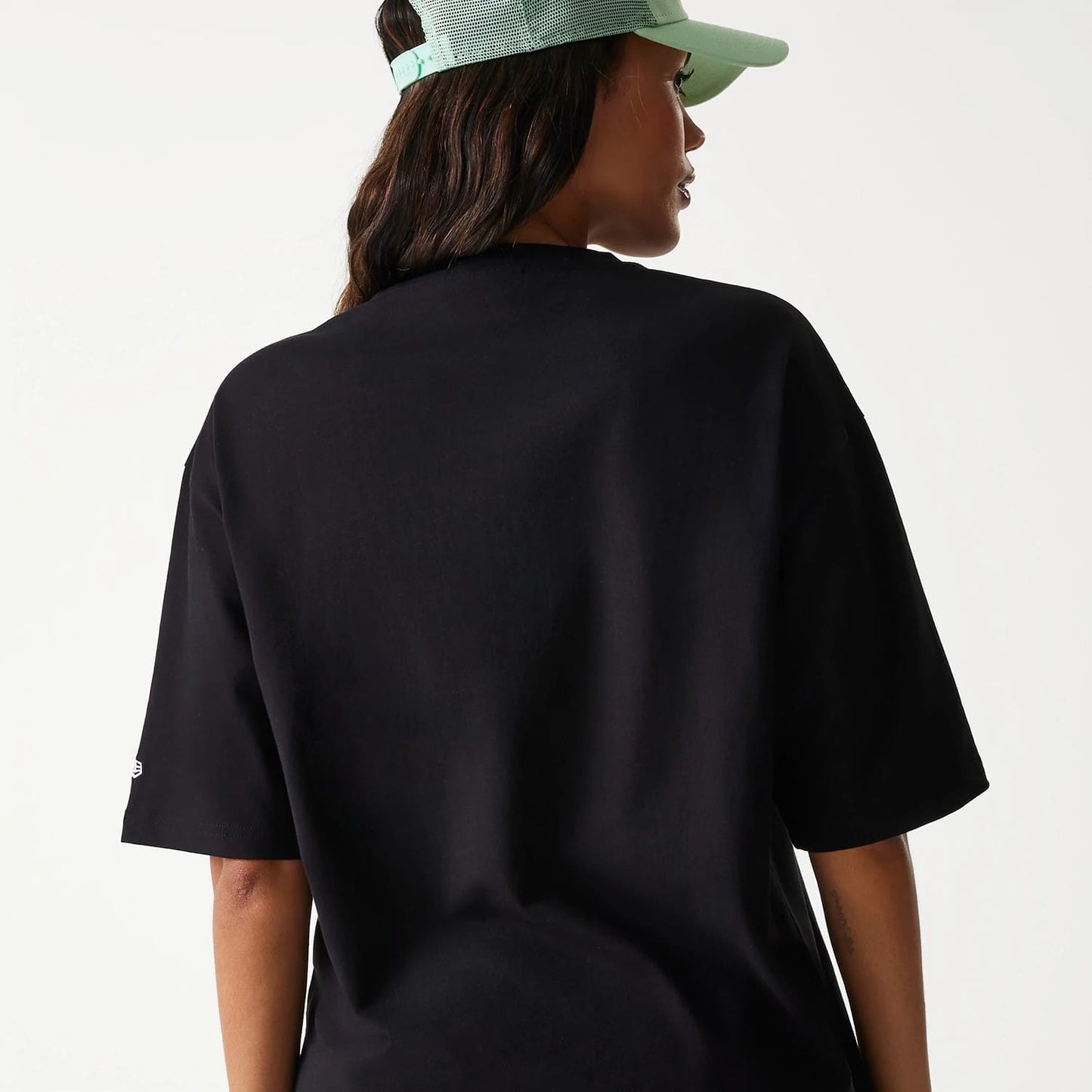 New Era Outdoor Graphic Black Oversized T-Shirt, rear view showing the plain black back with relaxed fit, short sleeves, and a small raised New Era logo on the left sleeve above the hem.