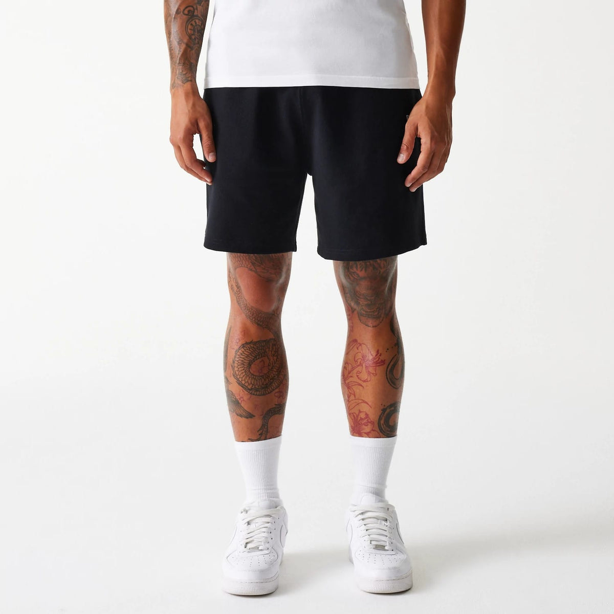 New Era LA Dodgers MLB Pique Black Shorts, front view showing the solid black design worn by a model, reaching above the knees, with no visible logos or detailing on the fabric.