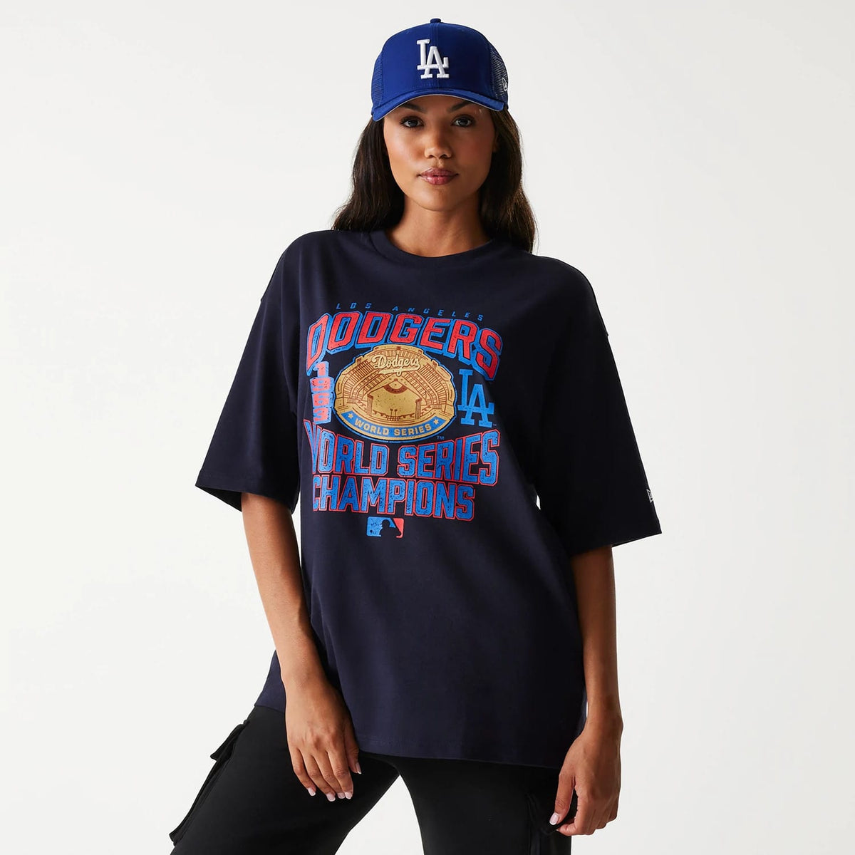 New Era LA Dodgers MLB World Series Navy Oversized T-Shirt, on-model view showing detailed front print of a World Series Champions graphic with a raised Dodgers logo, styled with a blue cap featuring an embroidered LA logo.