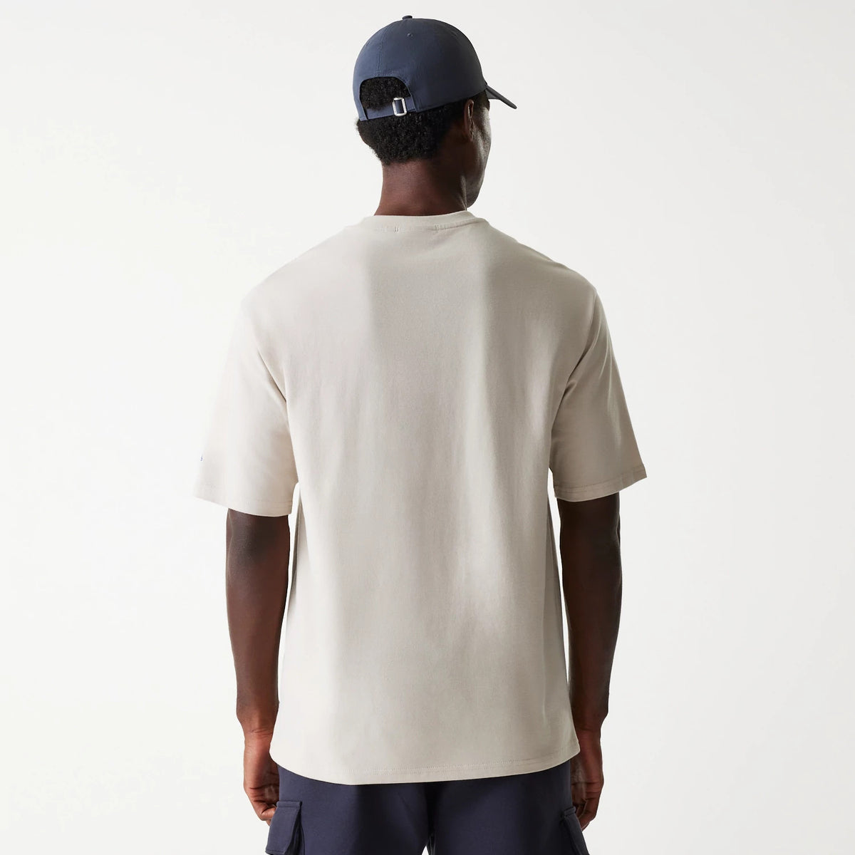 New Era LA Dodgers MLB Floral Graphic Cream Oversized T-Shirt, rear view showing the cream fabric with loose short sleeves and a relaxed fit, worn by a model with a navy cap featuring a debossed logo on the back strap.