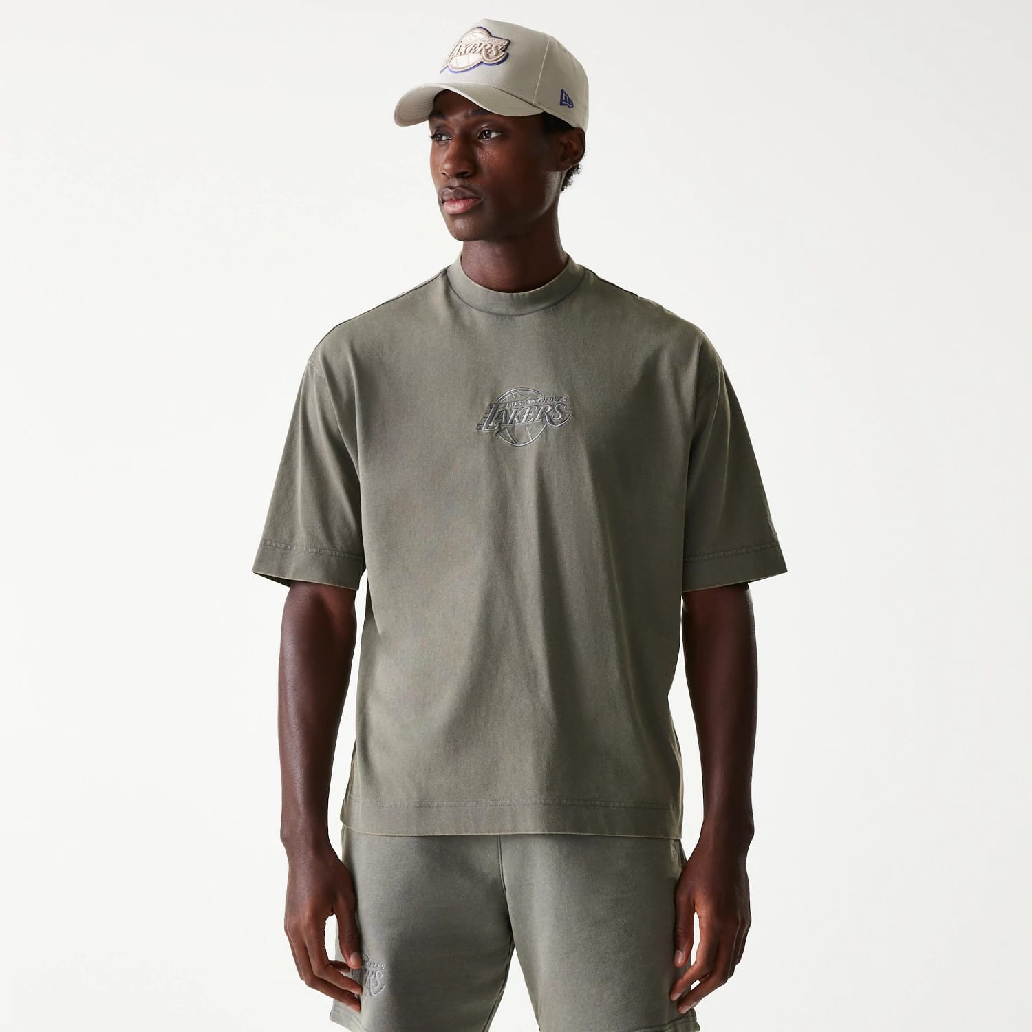 New Era LA Lakers NBA Washed Grey Box T-Shirt, front view showing a debossed Lakers logo centred on the chest, worn by a person with short sleeves and a relaxed fit, paired with matching grey trousers.