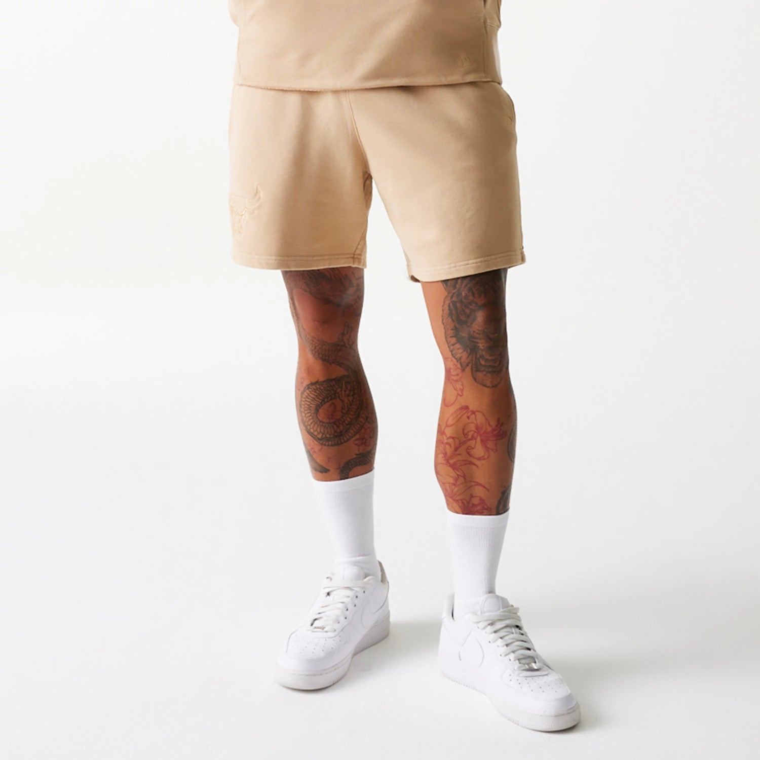 New Era Chicago Bulls NBA Washed Beige Shorts, front view showing the beige fabric with a raised Chicago Bulls logo on the lower left side near the hem, complemented by a relaxed fit and straight hemline.