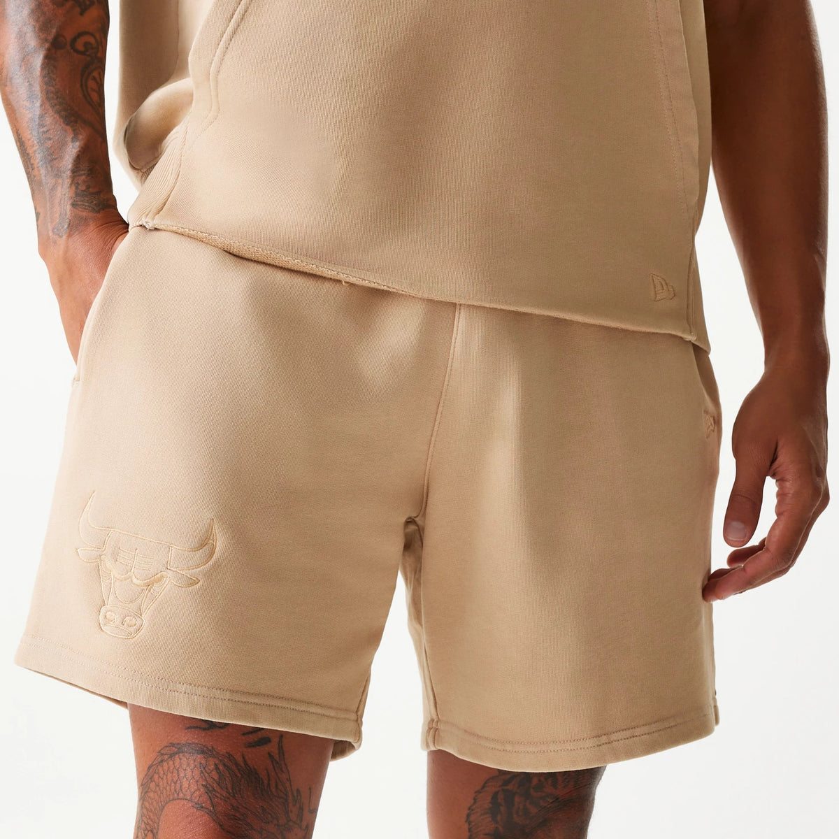 New Era Chicago Bulls NBA Washed Beige Shorts, front view showing the relaxed fit beige shorts with an embossed Chicago Bulls logo on the left thigh and a small embossed New Era logo near the hem on the right side.