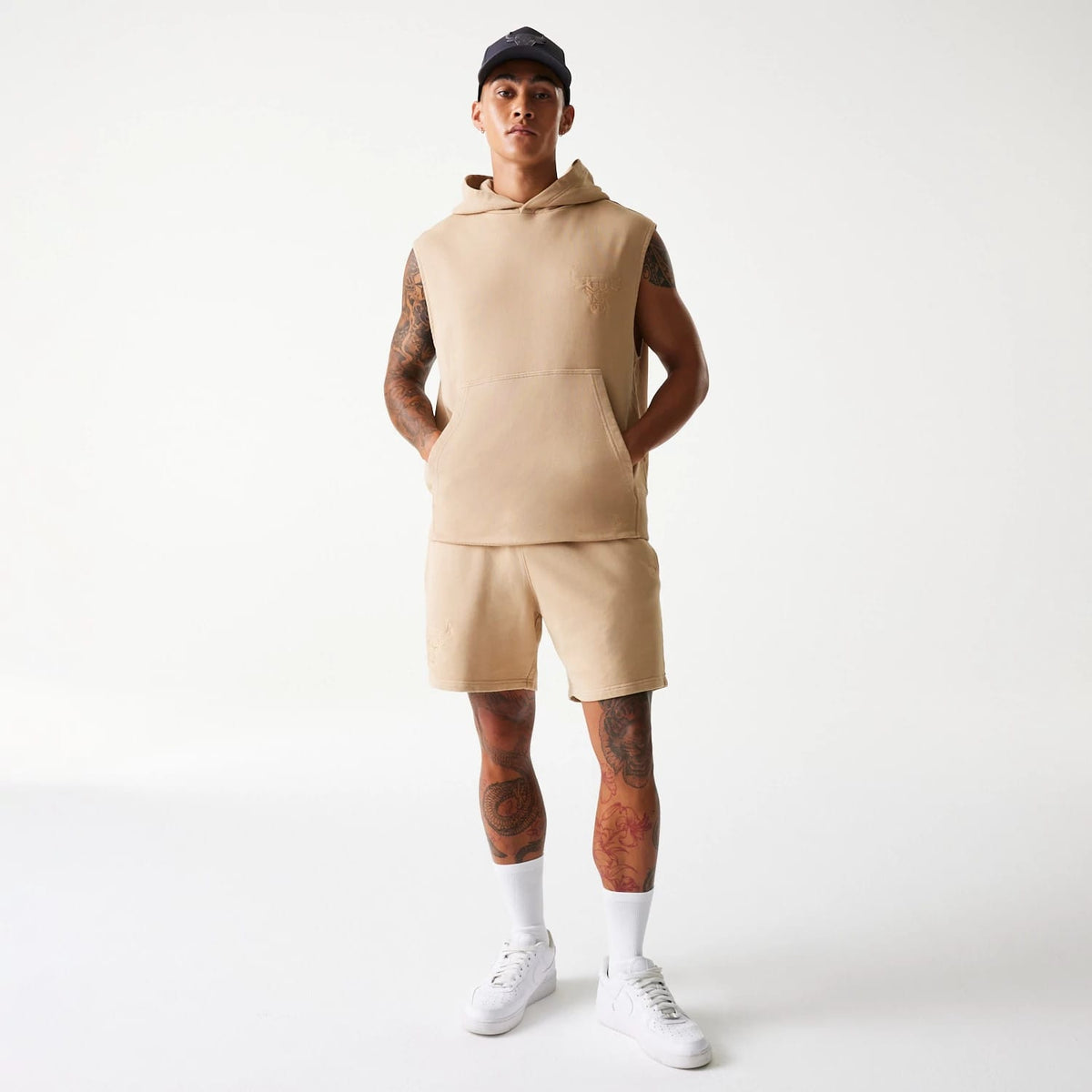 New Era Chicago Bulls NBA Washed Beige Shorts, on-model view showing the beige shorts worn with a matching sleeveless hoodie, a drawstring at the waist, and a small embossed logo on the left thigh.