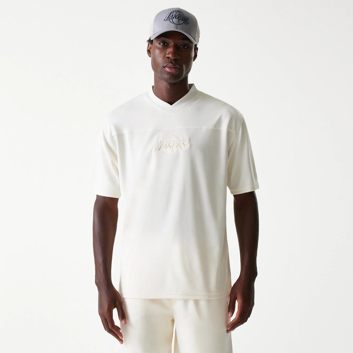 New Era LA Lakers NBA Tonal Open White Mesh Jersey, front view on a model with matching white shorts and a grey Lakers cap, featuring a subtle Lakers logo embroidered centrally across the chest.