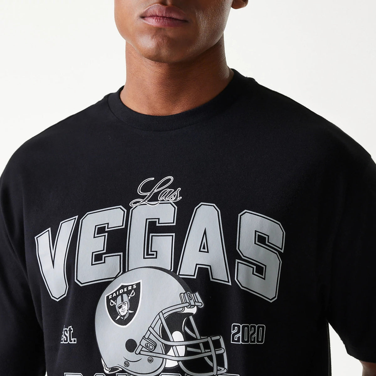 New Era Las Vegas Raiders NFL Helmet Black Oversized T-Shirt, front view showing the large graphic print with Las Vegas in bold above a detailed Raiders helmet logo in grey and white on the black fabric.