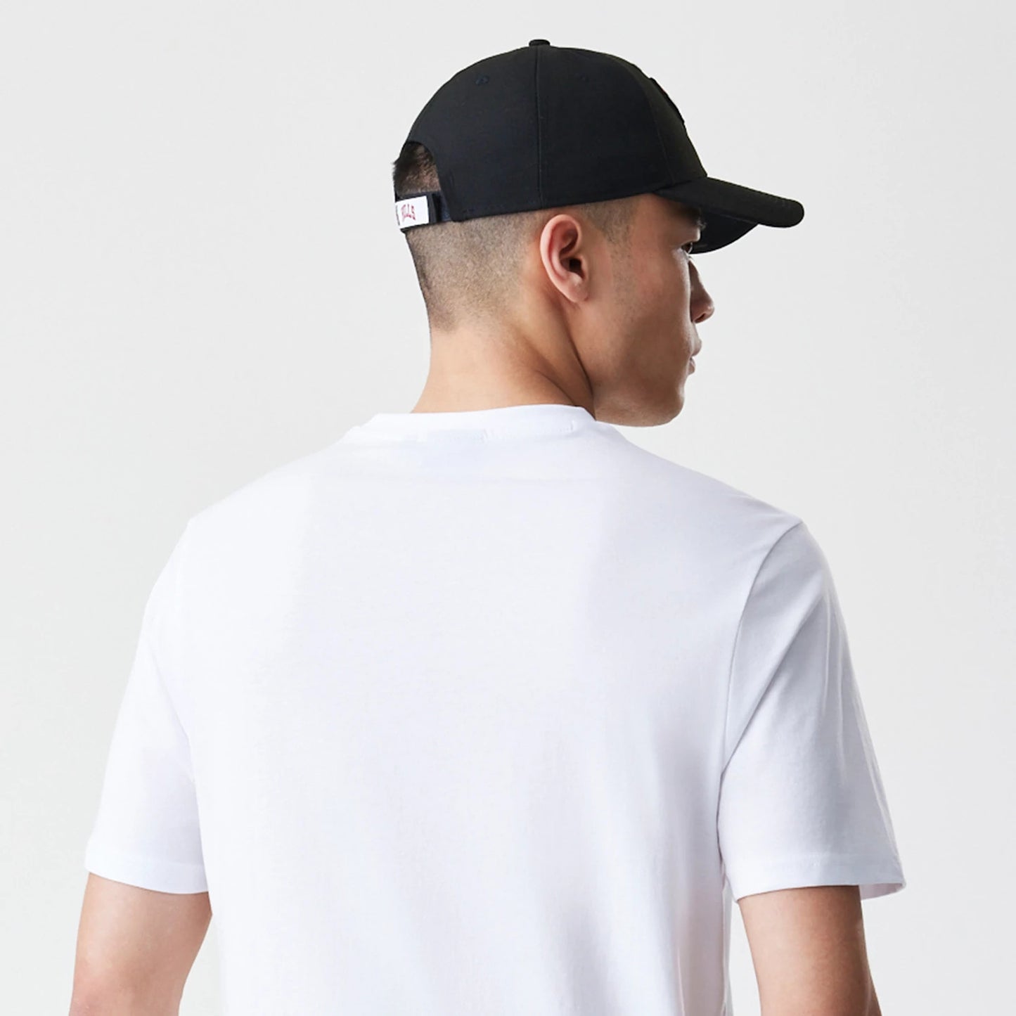New Era Chicago Bulls NBA Stack Wordmark White T-Shirt, on-model rear view showing the plain white back of the t-shirt and a black cap with a small embroidered logo on the adjustable strap at the back of the head.