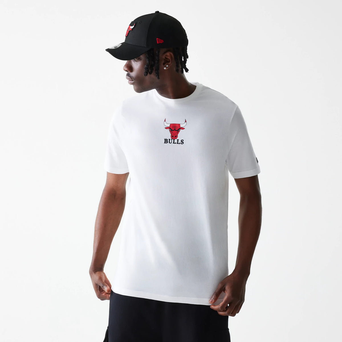 New Era Chicago Bulls NBA Logo White T-Shirt, on-model view showing the white tee with the red and black Chicago Bulls logo centred on the front, worn by a model also wearing a black cap with a raised red logo.
